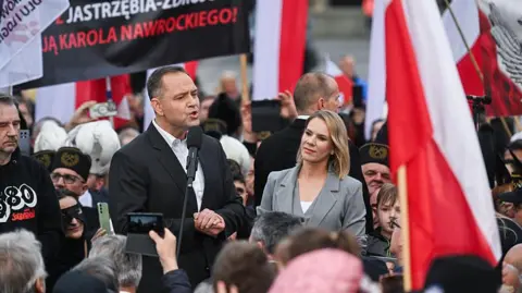 Getty Images Poland's conservative presidential candidate addresses supporters wearing a black jacket alongside a woman