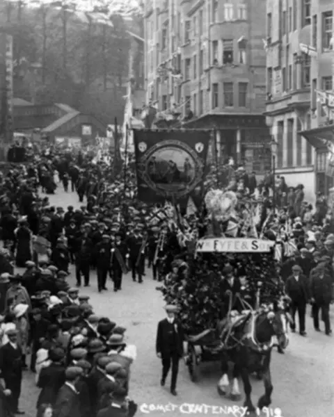 Kevin Green Crowds parade down a street in an old black and white photo