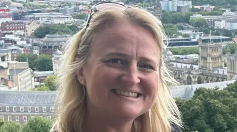 Angharad Salmond, a blonde woman wearing a black t-shirt and sunglasses on her head