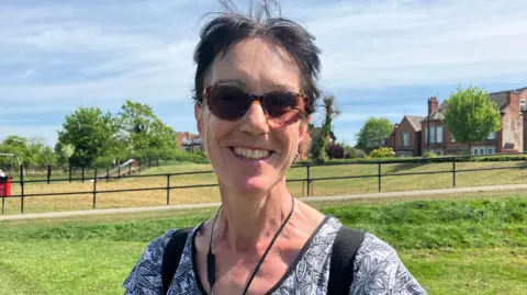 Woman with sunglasses and floral top on a footpath.