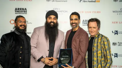 Arun Kapur and Gurjant Singh Four men stand together against a white wall with logos