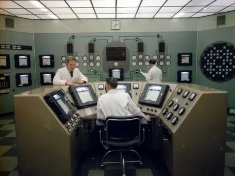 Courtesy Nuclear Restoration Services Inside the Chapelcross plant with men in white coats and large display panels with a lot of dials and buttons