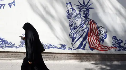 EPA File photo showing an Iranian woman walks past an anti-US mural in Tehran, Iran (16 August 2023)