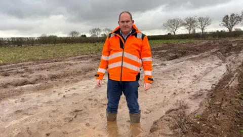 Jon Hammond standing in a muddy field