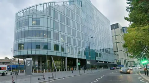 Google A multi-storey glass building above a busy roadway.