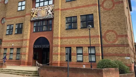 Brian Farmer/BBC St Albans Crown Court: a yellow and orange brick building. A set of stone steps is leading to the entrance. Above the entrance is a sign saying "Crown Court".