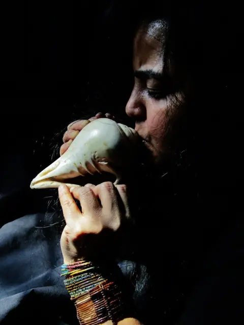 Preeti M Blowing a conch shell