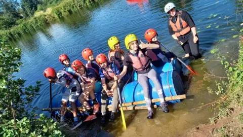 RAF Benevolent Fund Kids sitting on a make-shift raft on the edge of a lake