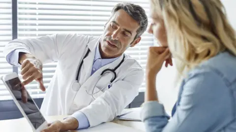 Getty Images A doctor shows something on a tablet computer to a patient