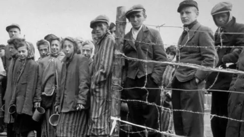 Prisoners standing by a fence at Belsen concentration camp