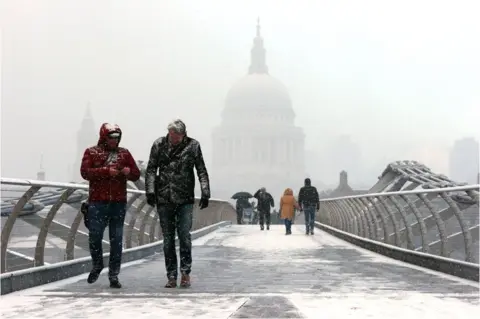 PA People walk over Millennium Bridge in the snow, in London