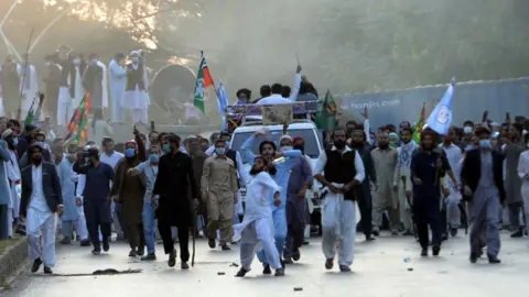 EPA Protestors react after police fired tear gas shells to stop them reaching the French embassy in Islamabad