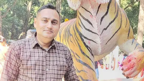 Saroj Chapagain Saroj stands in front of a tiger statue 