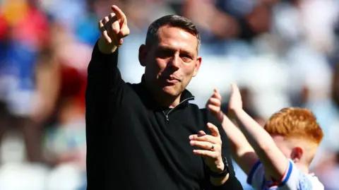 Reading FC boss Leam Richardson points ahead, wearing black fleece