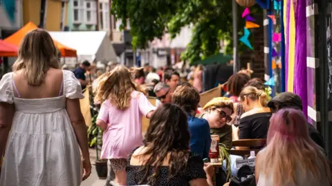People sitting outside in summer enjoying food and drink in the Norwich Lanes