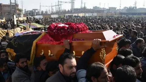Reuters Several men carry a coffin through a huge crowd