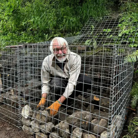 Peak Park Conservation Volunteers Man placing stone inside a wire cage