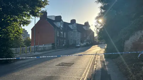 Alice Cunningham/BBC Houses have been cordoned off on the road