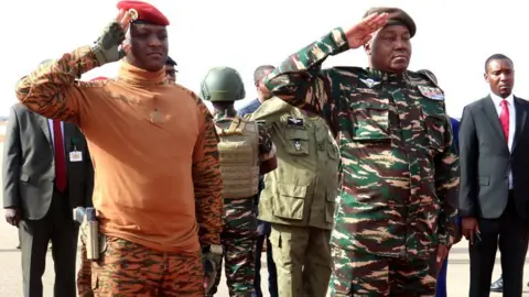 AFP Niger's General Abdourahamane Tiani (R) salutes next to his Burkinabe counterpart Captain Ibrahim Traore (L) upon his arrival in Niamey on July 5, 2024.