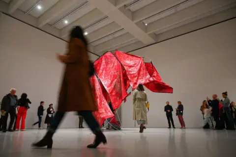 Jaap Arriens / Getty Images Visitors observe the red sculpture "Ghosting" by Congolese artist Sandra Mujinga at the opening of the new Museum of Modern Art in Warsaw.