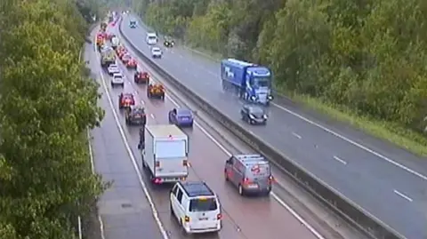An overhead view of a motorway, where the closest side to the camera is heavily congested with traffic.