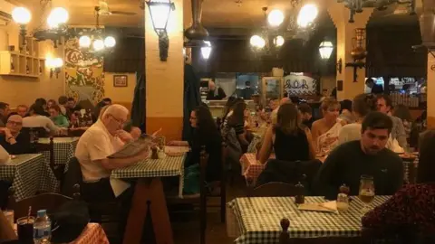 Casa Italia A number of customers are sitting at tables with gingham table cloths inside the restaurant. 