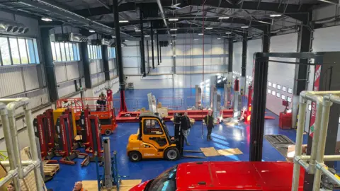 Alison Stephenson Inside the new operational services centre. There is forklift at the centre and a parked red van in the forefront. 