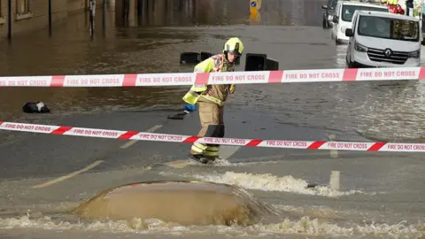 Dan Jessup A firefighter stares at water pumping out of the road into a flooded street