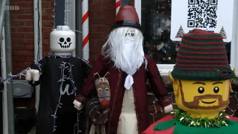 Four large figures stand outside Mr Girling's house including a Halloween Lego man, a dog, a wizard and an elf.