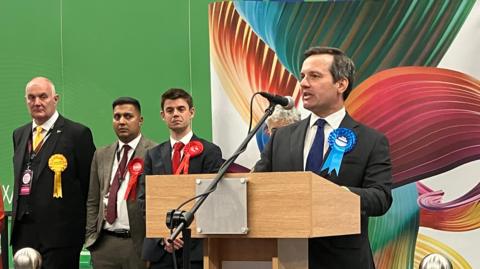 Chris Green speaks at the podium at the Bolton West count having lost his seat