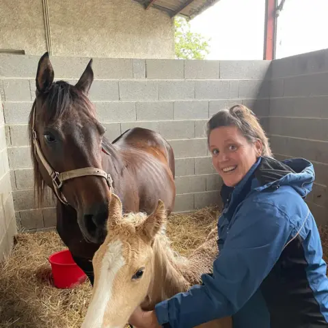 Supplied A photograph of Corinne smiling with two horses next to her