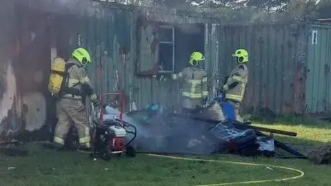 Firefighters tackling a blaze at some metal containers at Trimsaran rugby club.
