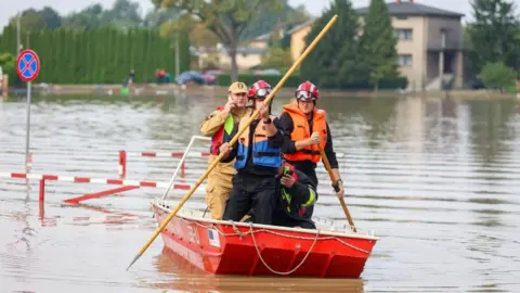 EPA Rescuers use poles to move a raft in a flooded areas of Czechowice-Dziedzice, south Poland