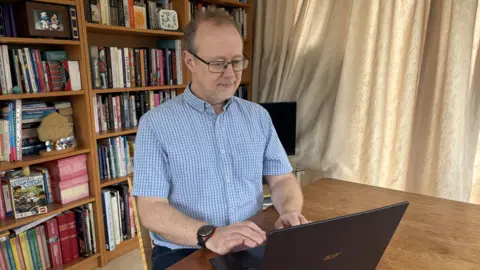 Sean McManus Sean McManus wearing a short sleeved shirt and working at his laptop