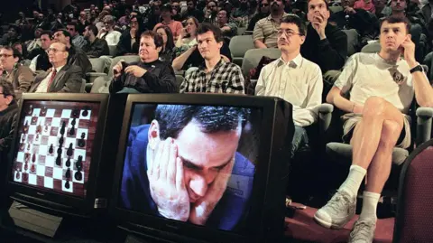AFP via Getty Images Fans watch a chess game 06 May 1997 in New York between World Chess Champion Garry Kasparov (on TV monitor) and the IBM Deep Blue computer. The game was televised from the playing room to this auditorium where chess experts analyzed each move. 