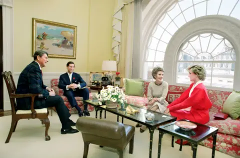 Universal Images Group via Getty Images The president, prince, first lady and princess all sit on sofas and chairs in formal attire as they chat in the White House.