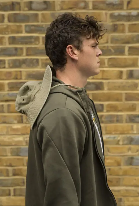 Martyn Ewoma Kamakaze in front of a brick wall.