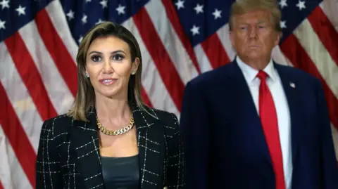 Getty Images Habba standing and speaking in front of American flag with Trump beside her