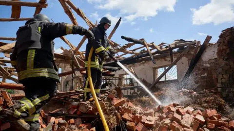 Ukrainian rescuers work at a site of a rocket hit to the riding hall of the Equestrian Center of the Veterinary Academy in Mala Danylivka village near Kharkiv