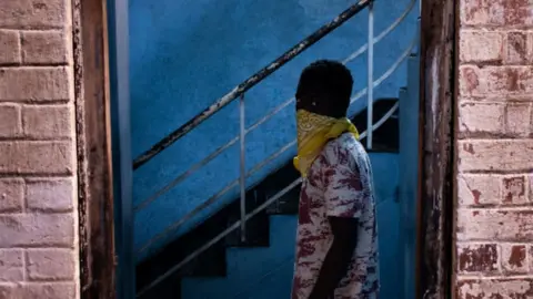 AFP A foreign migrant wears a bandana as he leaves a building in the Kwa Mai Mai area in Johannesburg, on May 10, 2020.