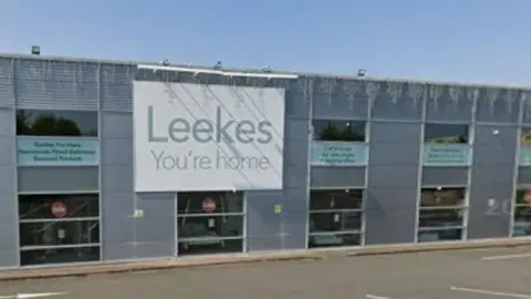 The front of the shop which has a sign saying "Leekes You're home". The shop is grey with windows. 