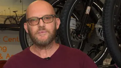 A man wearing glasses pictured in a bike shop