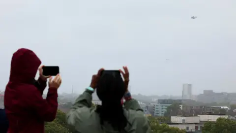 Isabel Infantes/REUTERS People watch as a helicopter believed to be carrying U.S. President Donald Trump flies after leaving the U.S. ambassador's residence Winfield House, on the way to Windsor, in London, Britain, September 17, 20
