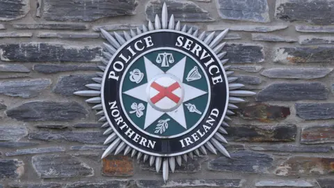 A PSNI logo on a brick wall
