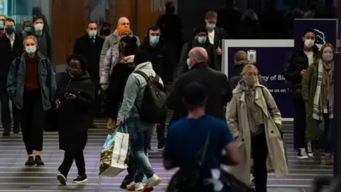 PA Media Commuters at Birmingham New Street train station, as mask wearing on public transport becomes mandatory