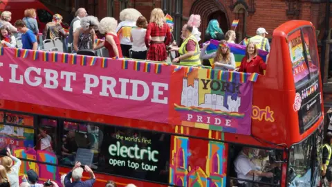 Visit York York Pride revellers on an open-top bus in York