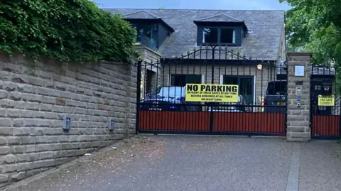 LDRS A main entry to a detached bungalow with wood and iron gates and a large yellow no parking sign