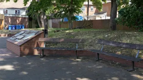 John Fairhall/BBC An area of seating in Upper Orwell Street in Ipswich, with trees in the background and paving in the foreground. Sun is shining through leaves in the trees, leaving most of the area under shade