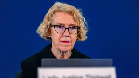 Reuters Chair of the inquiry Lady Justice Thirlwall at Liverpool Town Hall, looks on ahead of hearings into the murders and attempted murders of babies by nurse Lucy Letby. She has curly blonde hair and wears dark-framed glasses.