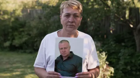 Francesco Tosto/BBC Vera holds a photo of her husband Volodymyr, who has been held in Russian captivity for years